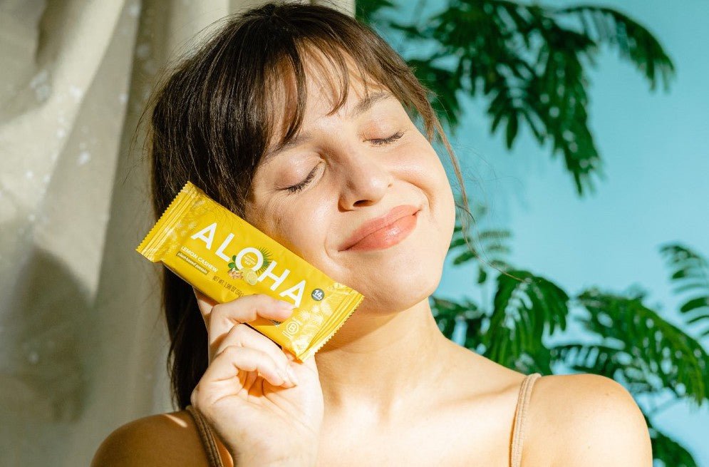 Holding an ALOHA cashew protein bar 